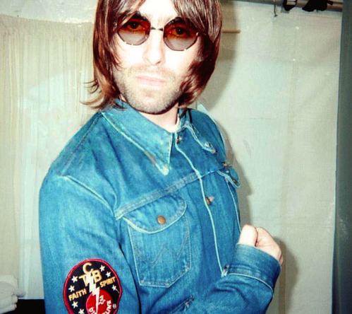 Oasis' Liam Gallagher wearing an Elvis Presley 'Taking Care of Business' lightning bolt badge on his denim jacket
