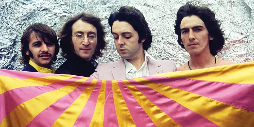 The Beatles with a psychedelia-inspired orange and pink 'rising sun' flag (credit: Pitchfork)
